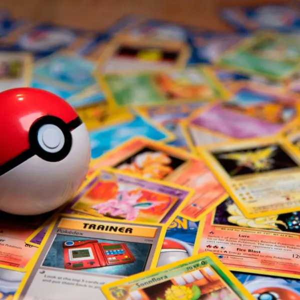 A scattered pile of Pokemon cards, collectible card game, with a pokeball on top.