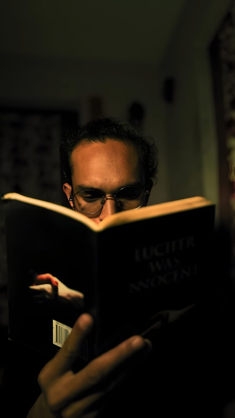 A man in glasses reads a book in a dimly lit room, evoking the dark mood of the Thornbird TV adaptation