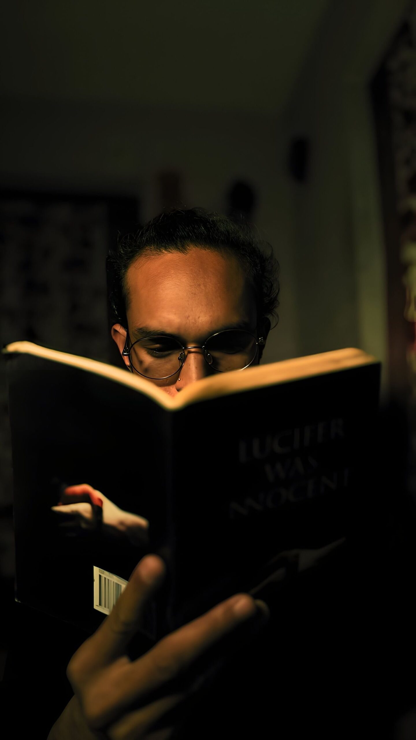A man in glasses reads a book in a dimly lit room, evoking the dark mood of the Thornbird TV adaptation
