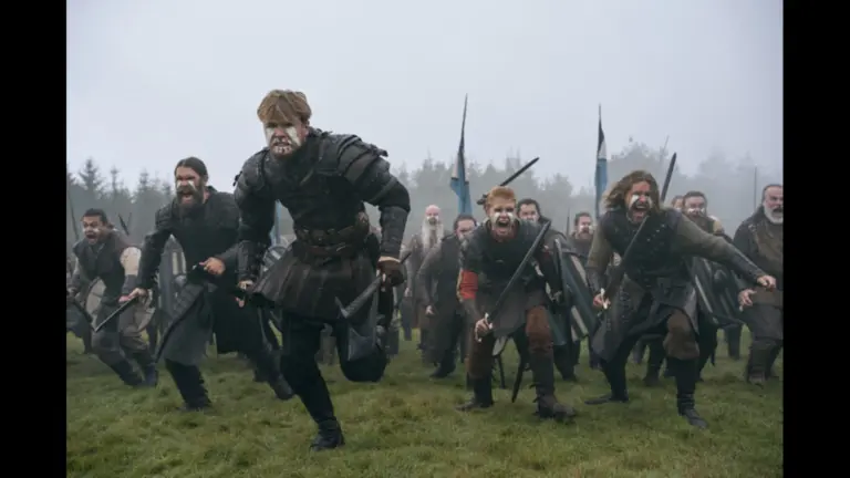Xavier Molyneux, Bernard Walsh, and Alina Tomnikov in Bloodaxe (2027) A group of men in medieval-style clothing and armor rush forward, holding weapons and displaying fierce expressions, amidst a foggy landscape.