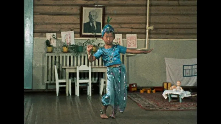 Scene from "Imperium" (2026) film, courtesy of BFI London Film Festival: A child in a sparkling blue outfit performing a dance in a room with a portrait on the wall and toys on the floor.