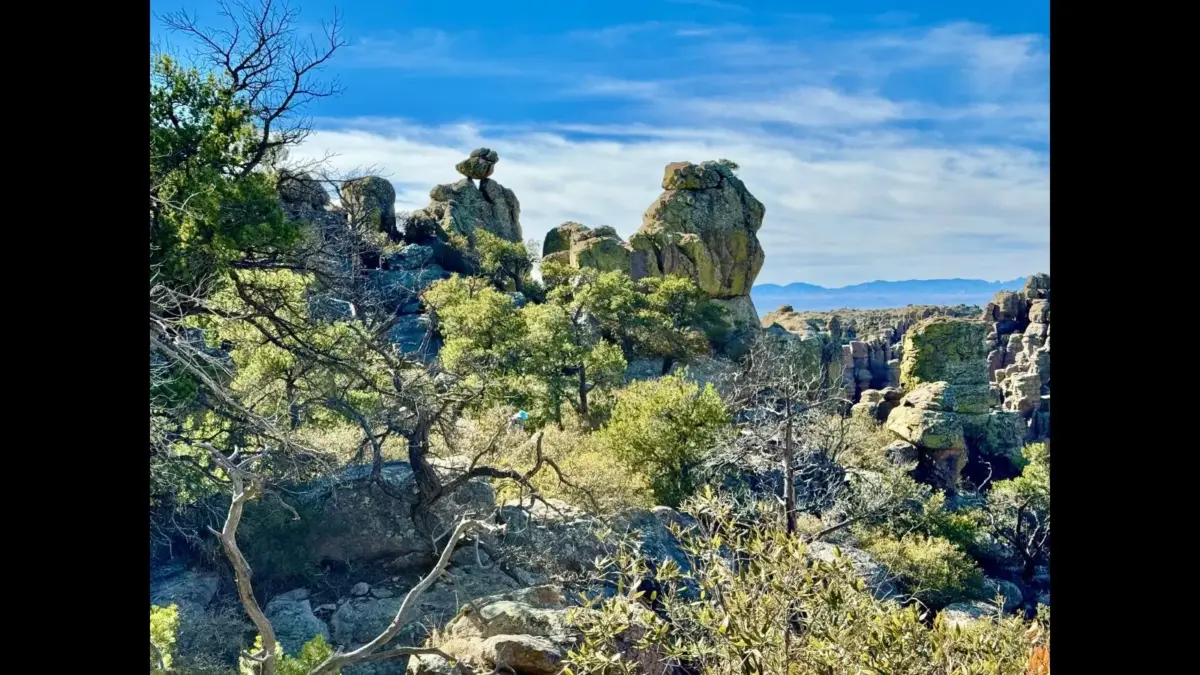 Chiricahua National Monument, Willcox, Arizona, A rocky landscape with unique rock formations and scattered vegetation under a bright blue sky.