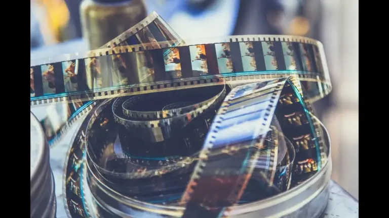 A close-up of a coiled strip of film reel, showcasing various images and film perforations. US film production
