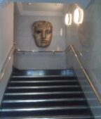 John Davidson BAFTA story: the bronze BAFTA mask mounted above a staircase at BAFTA headquarters on Piccadilly in London