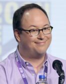 Lower Decks creator Mike McMahan smiles at a microphone during a Star Trek panel at San Diego Comic-Con in 2019