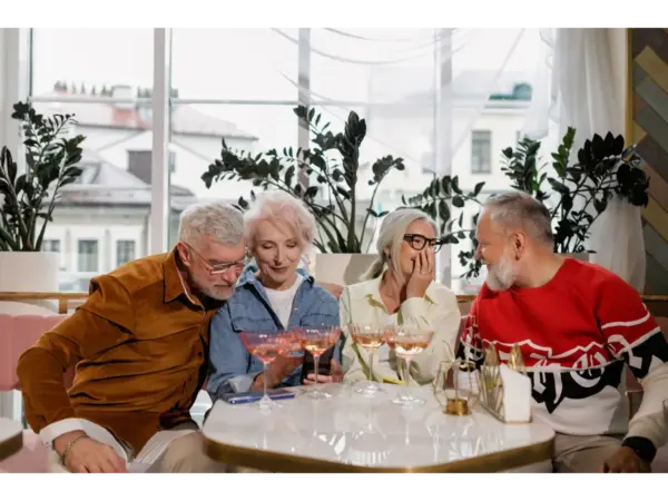 Four older adults enjoying drinks and conversation at a bright café, sharing laughter and connection, embodying longevity science secrets through social engagement and joy.
