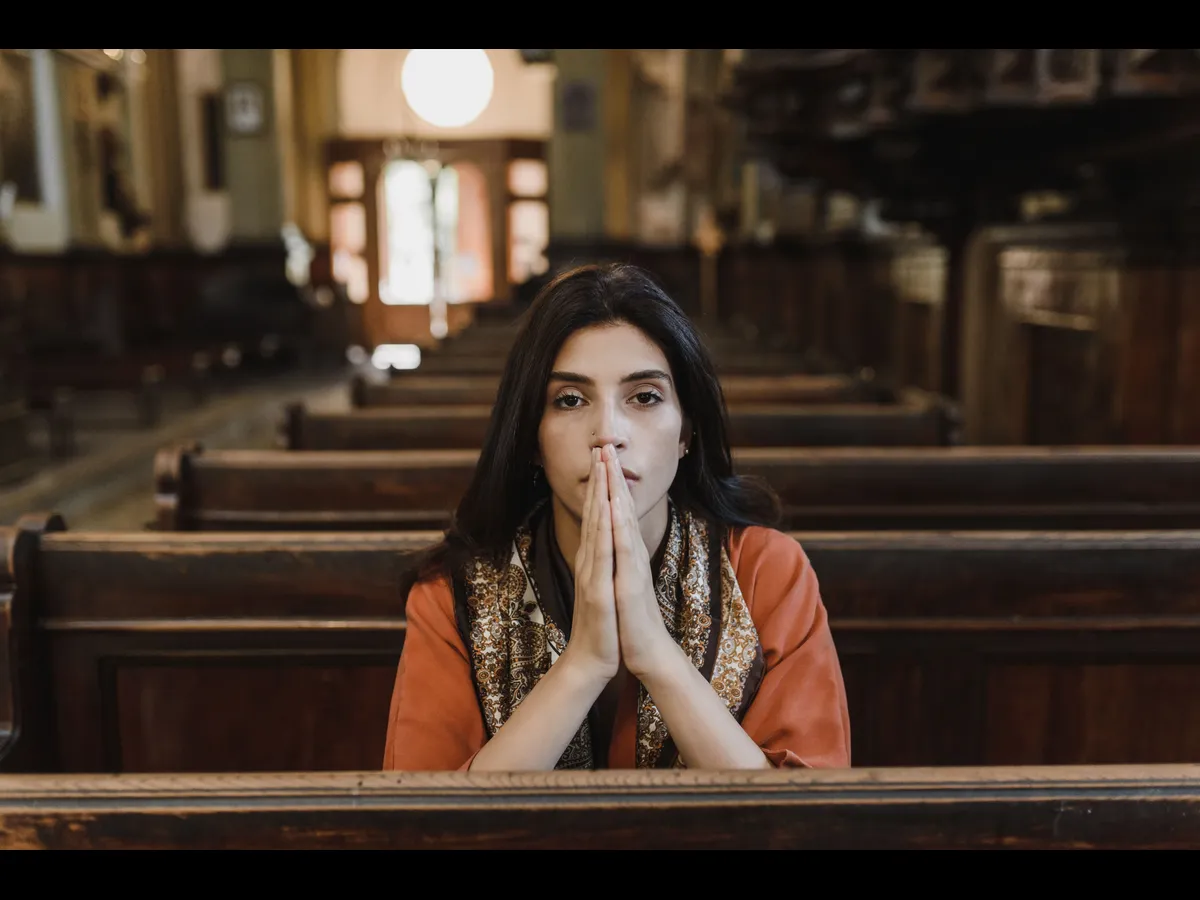In daily devotional, a woman prays while sitting in an empty chuch.