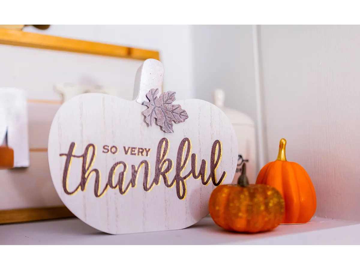 A "thankful" sign surrounded by small orange pumpkins adds seasonal charm while avoiding common Thanksgiving decorating mistakes that can make a space feel cluttered.