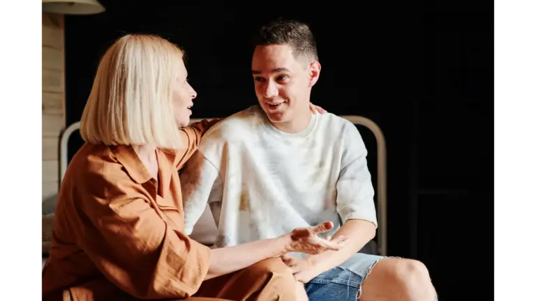 A mother and her adult son sit together having a warm, open conversation at home — a moment reflecting connection and adult kids independence.