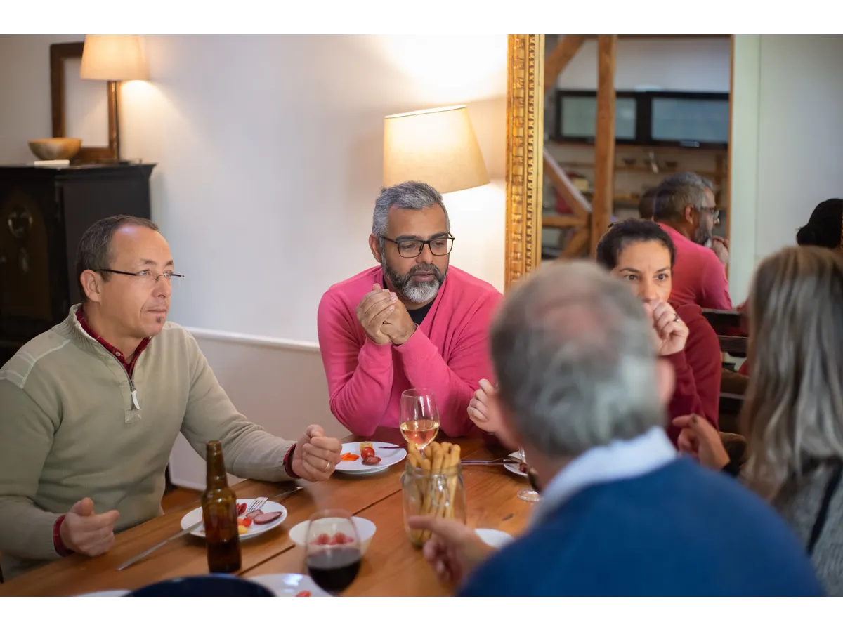 A family enjoying a casual meal indoors, sharing food and conversation while demonstrating the importance of boundaries with family during holiday gatherings.
