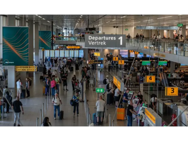Holiday travelers in the departure area of Amsterdam's Schiphol Airport, showcasing bustling travel activity.