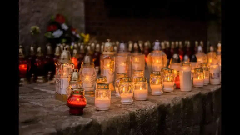 A serene scene of votive candles glowing softly in a cemetery during All Saints' Day.