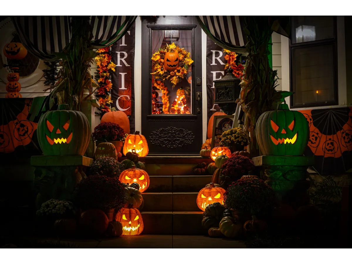 Decorated porch with glowing jack‑o'-lanterns on Halloween night creates the perfect backdrop for cozy, enchanting witchy Halloween decor.