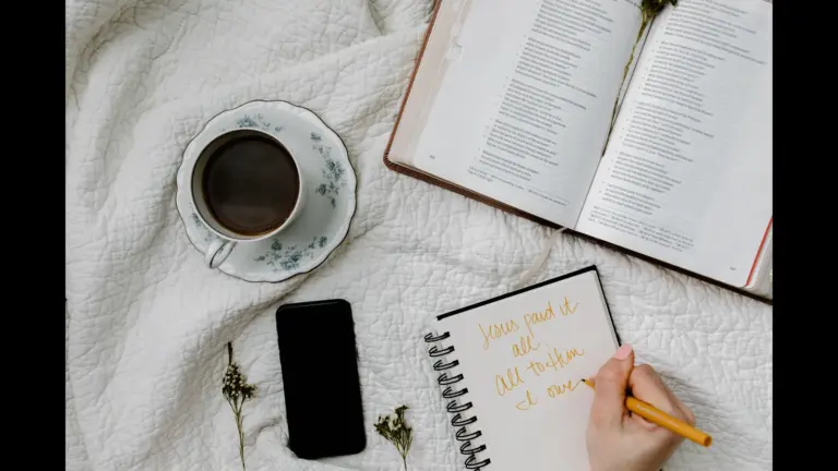 In daily devotional, a study area includes Bible, woman writing notes, and a cup of coffee.