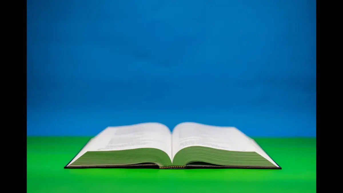 In daily devotional, a Bible is illluminated with light agains ta green and blue background.