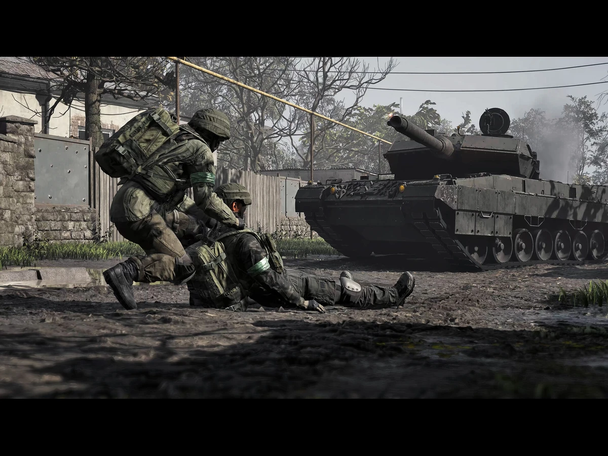 A soldier in WARDOGS dragging an injured comrade as a tank fires behind them.