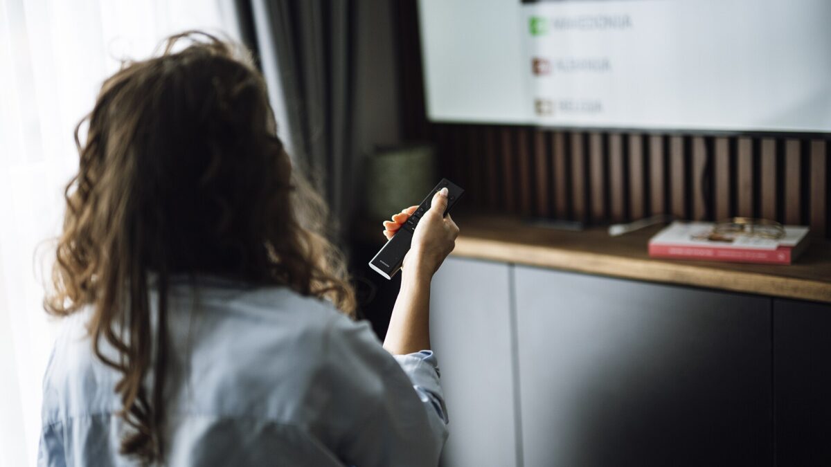 TV schedule this week: a person holds a remote control while watching television