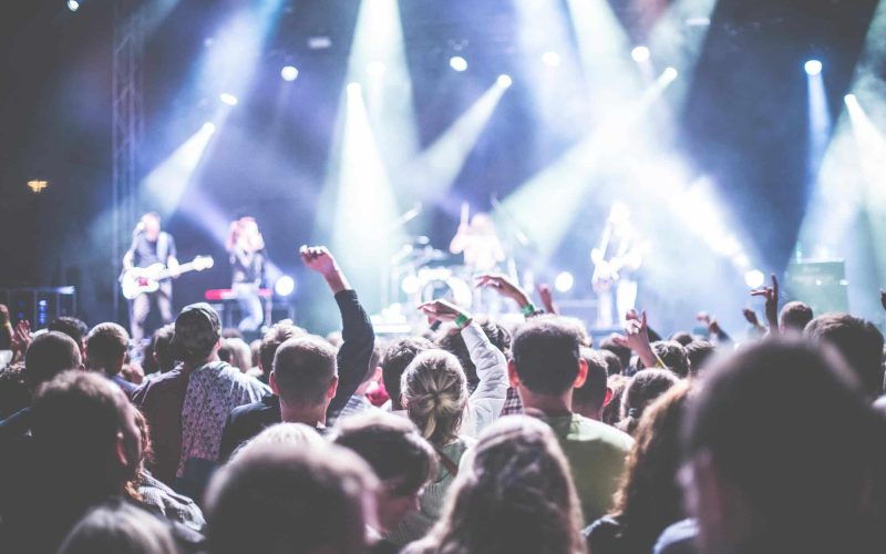 Energetic concert scene with a vibrant audience and band performing under bright lights. Ohana Festival 2025