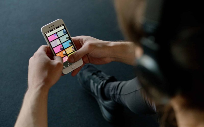 Close-up of a person listening to music on a smartphone while at the gym, focusing on a streaming playlist app, Spotify. Top 10 Streaming Artists on Spotify